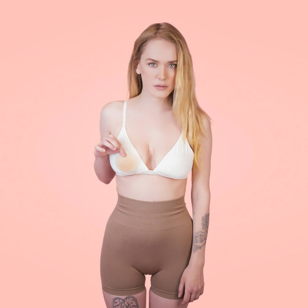 Helen Festin is holding beige nipple covers, demonstrating the size and true color.