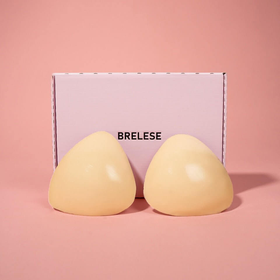 Beige Double Sticky Push-up bra inserts are showcased from the back, next to a pink Brelese box in front of a pink background.